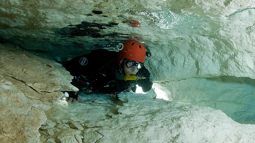 Tight Squeeze for a scuba diver in a flooded cave