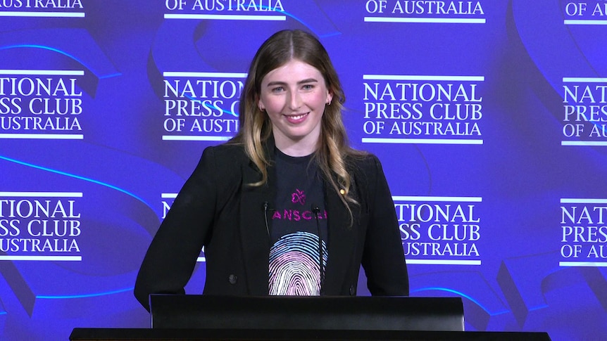 Georgie Stone at the National Press Club standing behind the podium during her speech