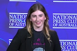 Georgie Stone at the National Press Club standing behind the podium during her speech