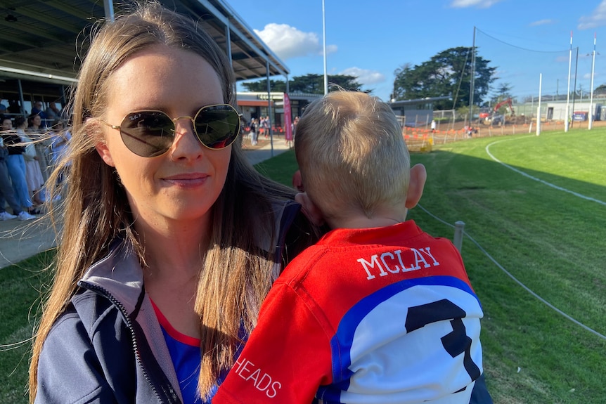 A woman in sunglasses holds a young boy.