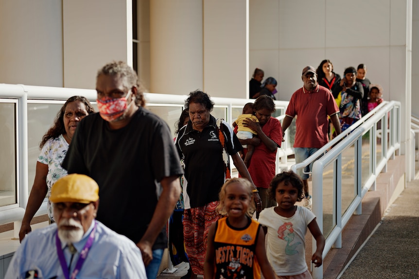 A group of people leave the NT Supreme Court. There are children and a man in a wheelchair at the front of the pack.