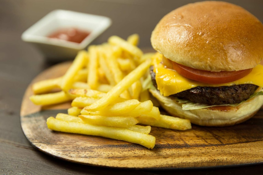 A burger and chips served on a wooden board.
