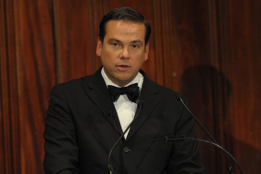 Lachlan Murdoch stands behind a lectern wearing a tuxedo