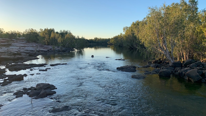 A rocky river surrounded by savannah scrub in late afternoon light