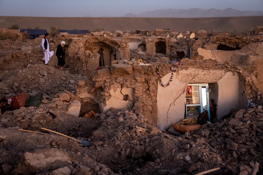 Two Afghan men search for victims after an earthquake.