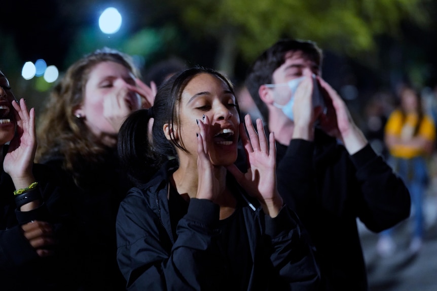 A young woman with her hands on her mouth is shouting in protest