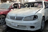 Cars with shattered windows are parked in a street after a wave of attacks in Baghdad.
