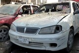 Cars with shattered windows are parked in a street after a wave of attacks in Baghdad.