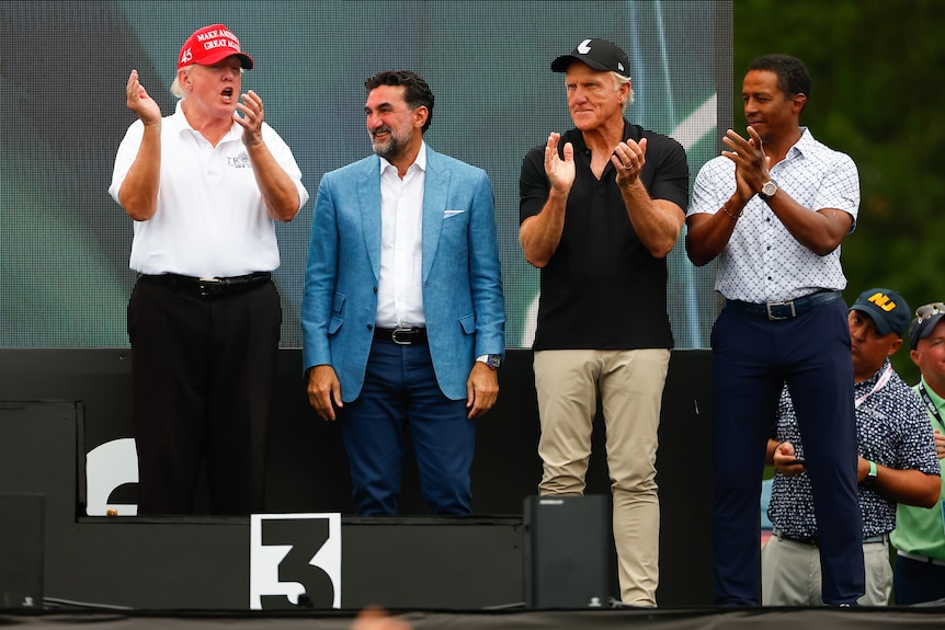 Donald Trump, Yasir Al-Rumayyan, Greg Norman and Majed-al-Sorour applaud on stage at a LIV Golf event.