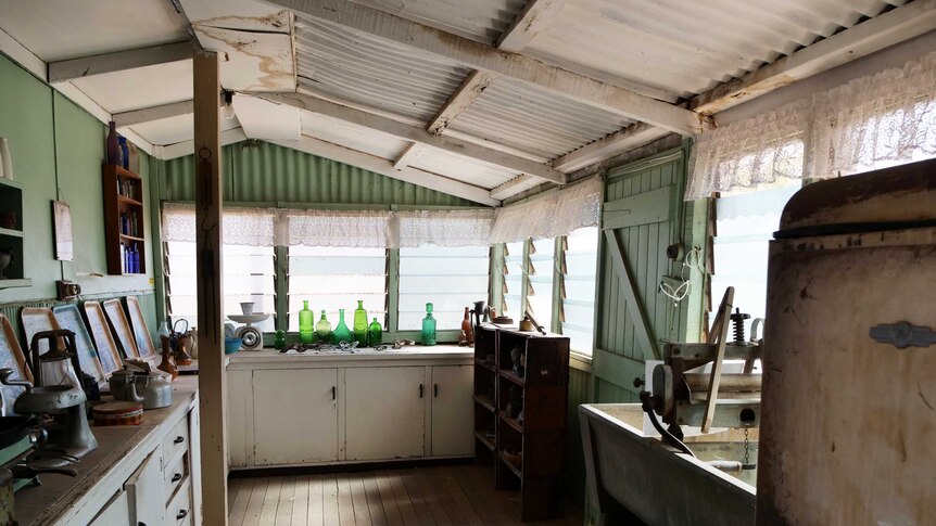 A photo of an old house with a tin room and green corrugated walls. The fittings are from the 1950s.