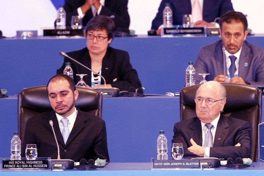 Soccer administrators sit behind tables during a meeting