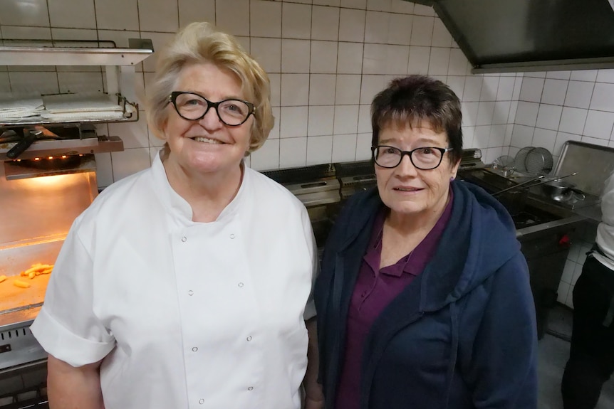 Two older women in a commercial kitchen.