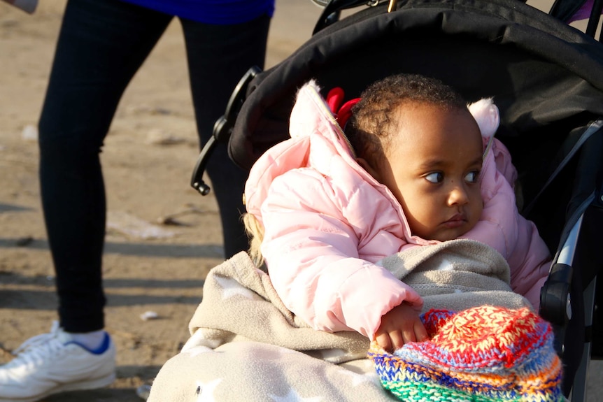 A baby girl sits in a pram