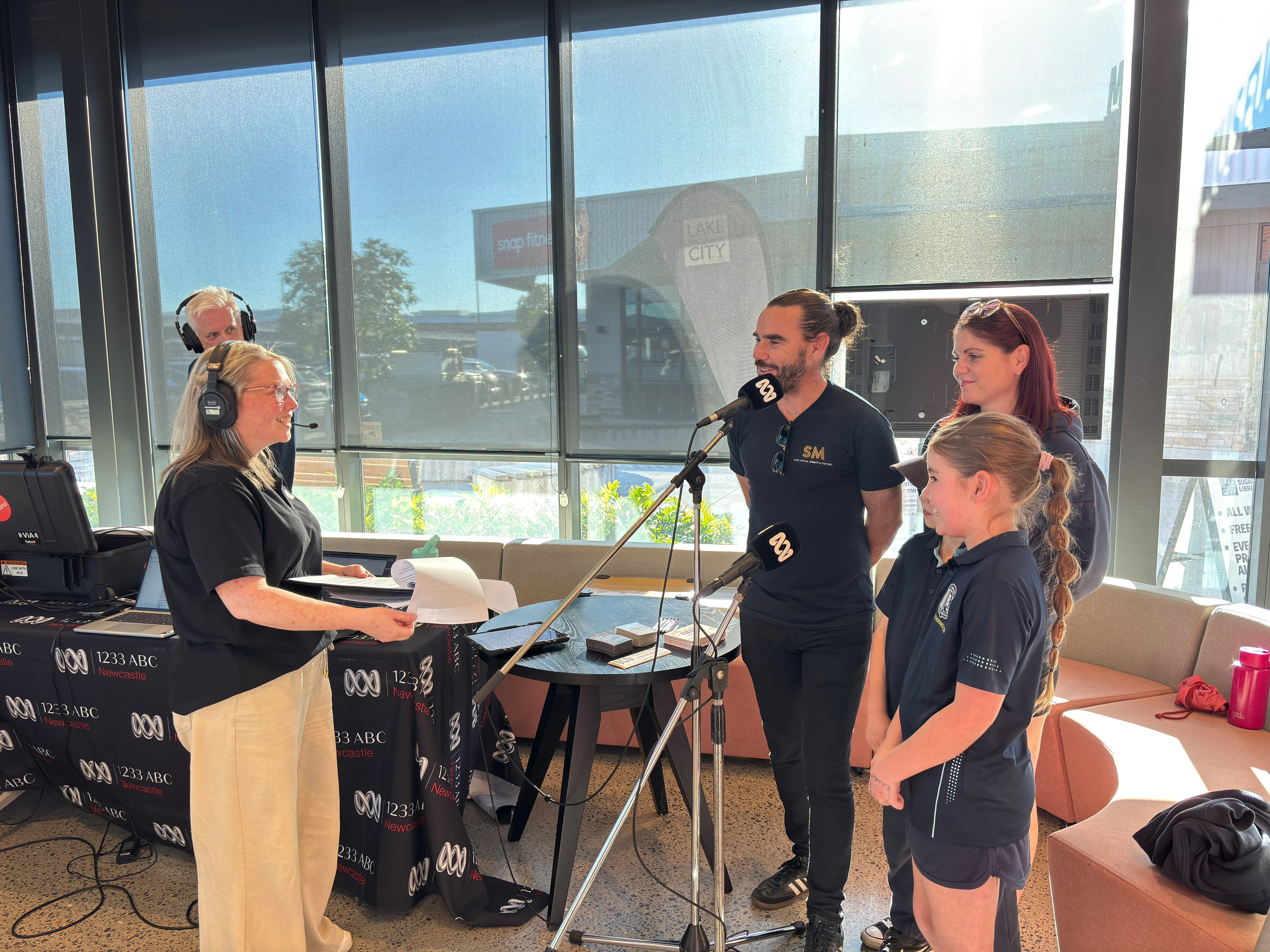 Five people standing at microphones talking