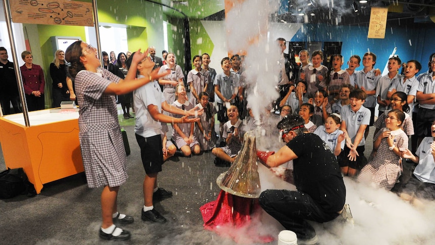 Students laugh as they take part in a science experiment that explodes inside Questacon.