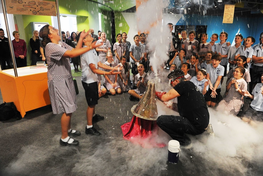 Students laugh as they take part in a science experiment that explodes inside Questacon.