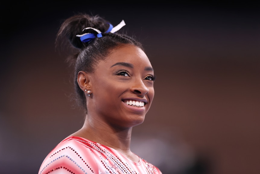 Headshot of woman smiling during her gymnastics warm up during the Olympics  