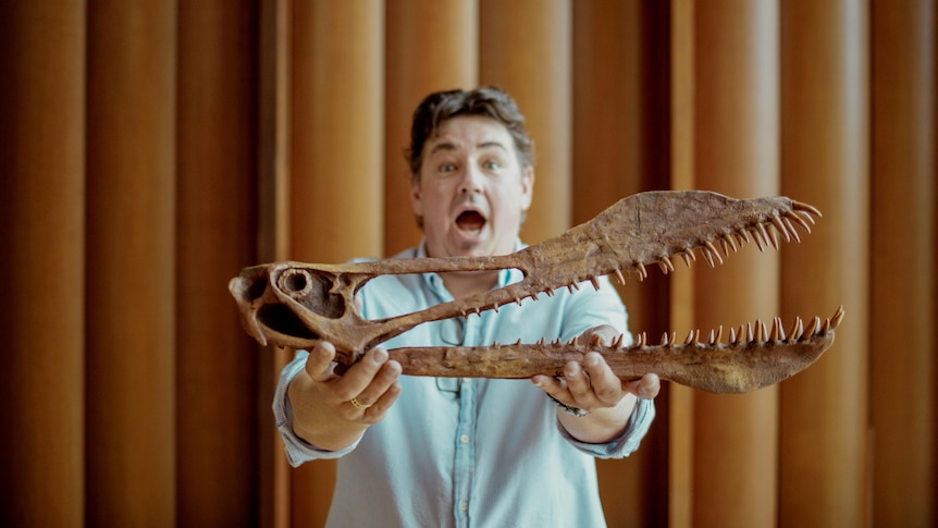 man holding dinosaur skull