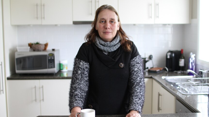 Sylvia Lord at the kitchen bench with a coffee cup inscribed with - It's not my fault, I'm awesome