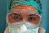 A female health worker in full protective gear with fogged up goggles on