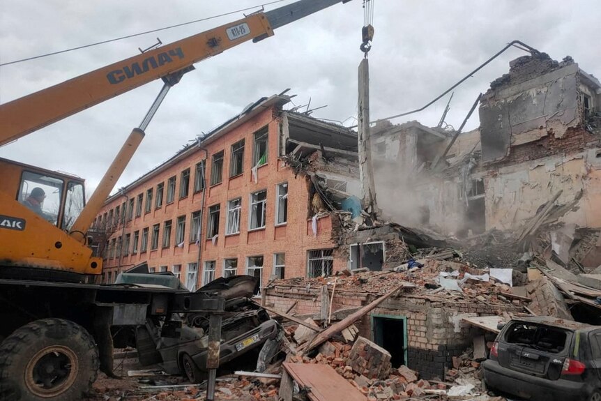 Rescuers remove debris from a school building damaged by shelling