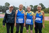 Four women standing together, wearing athletics badges with participant numbers on them.