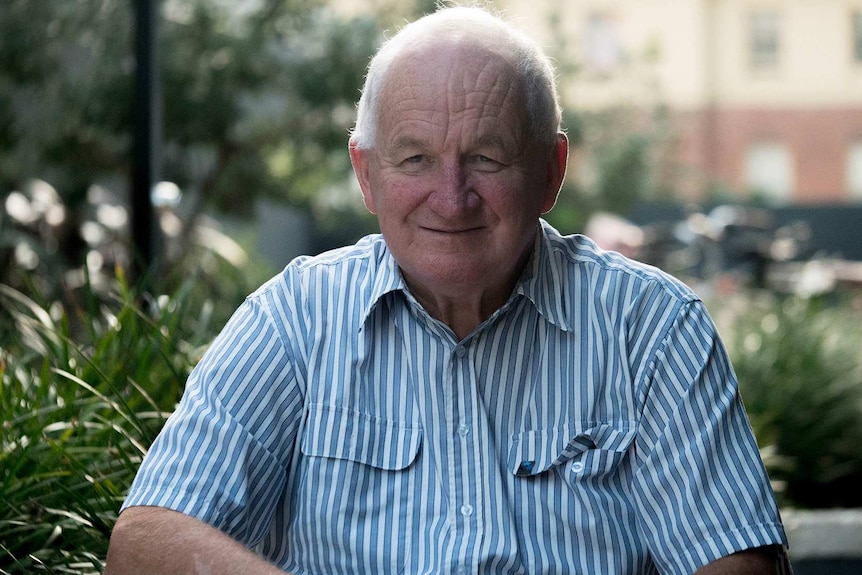 Man in a striped shirt against a green blurred background.