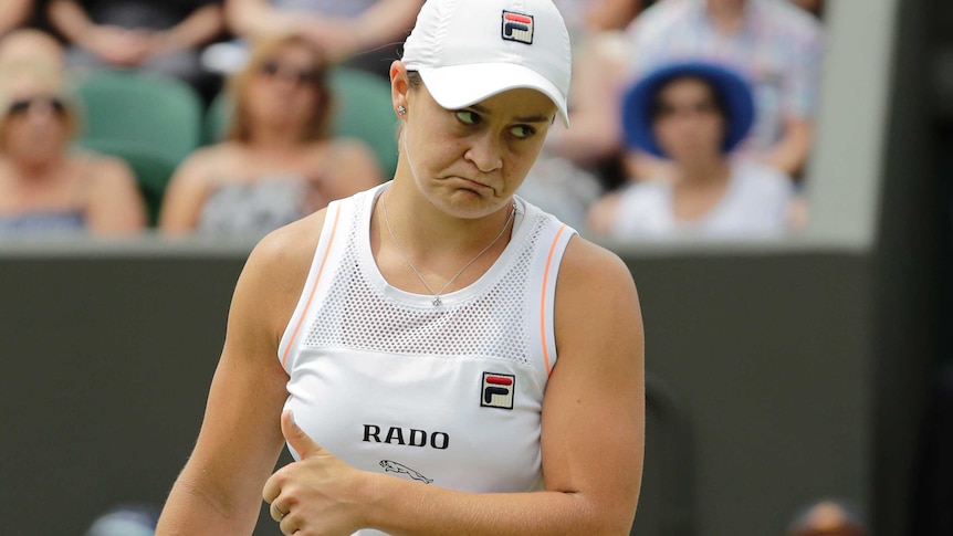 Ash Bart frowns while giving a thumbs on a tennis court