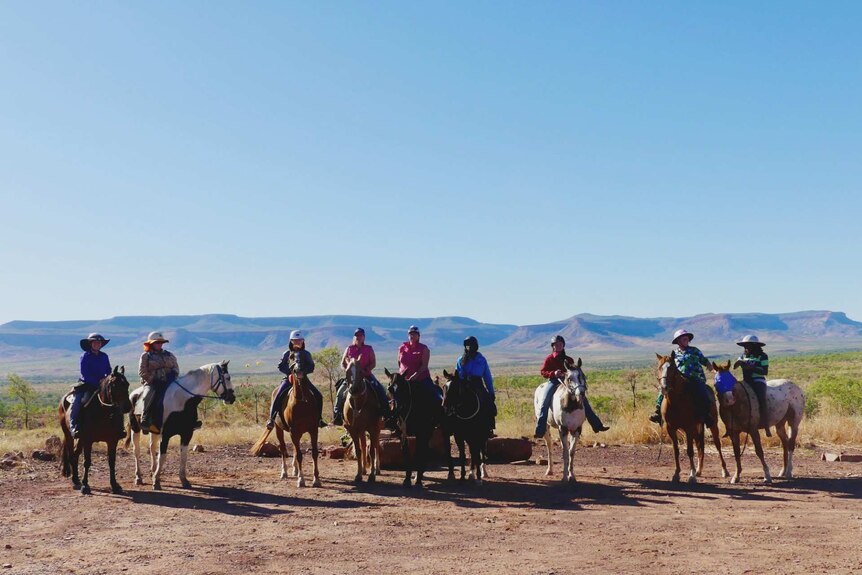 Nine horses and riders lined up with Cockburn Range in the background
