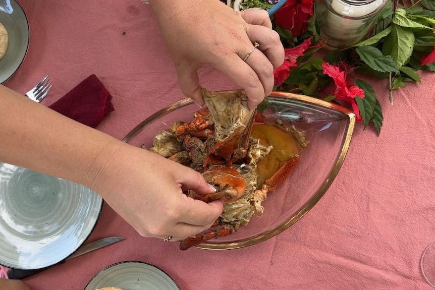 Cangrejo de barro jugoso en bandeja sobre una mesa decorada con un mantel rosa y flores. 