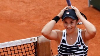 Ash Barty hold her hands on her head while holing a tennis racquet