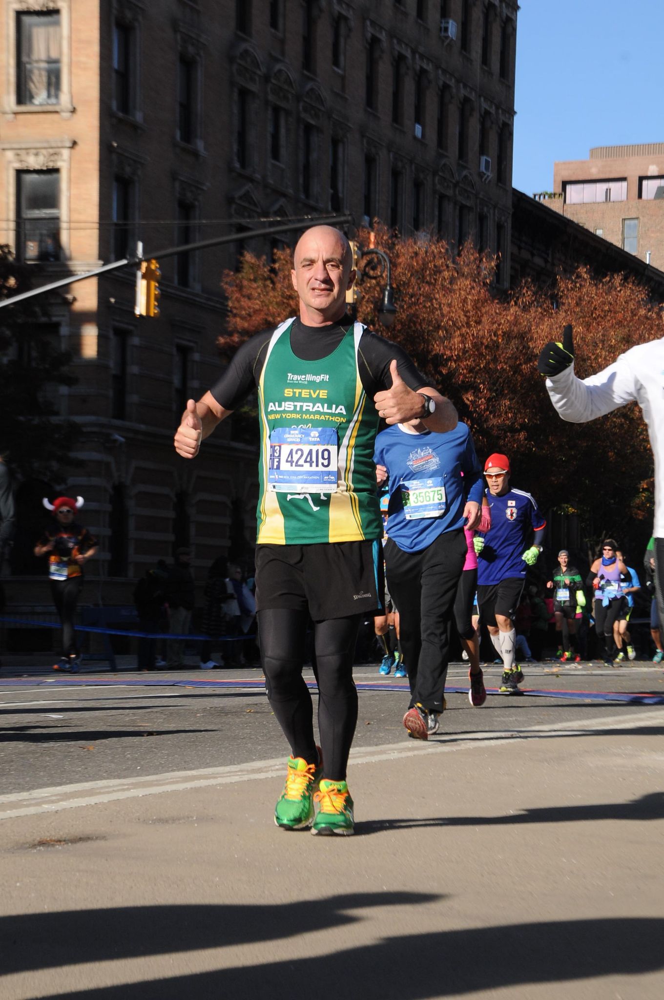 A marathon runner gives the thumbs up as he comes down a city street.
