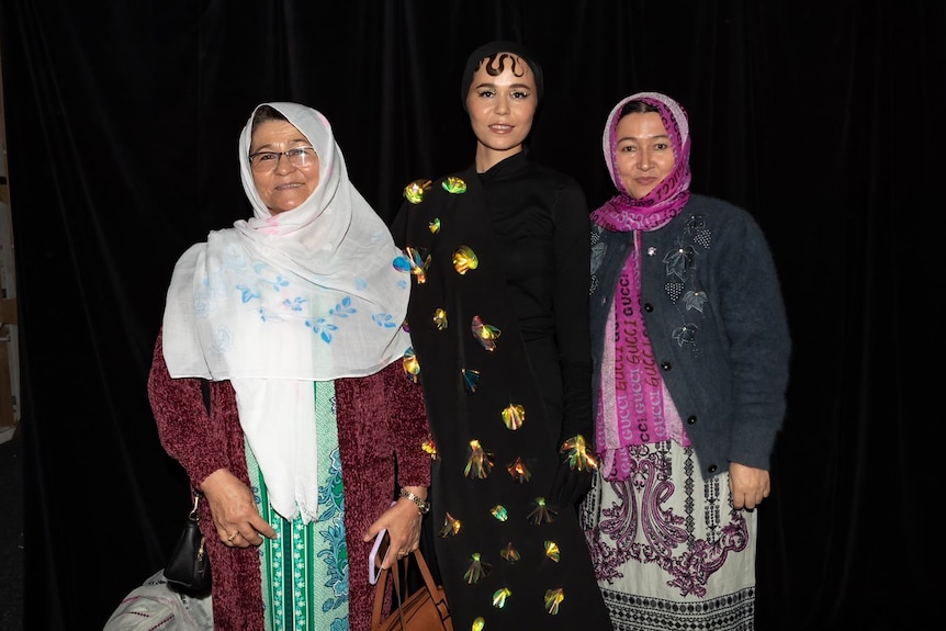 Three women wearing Afghan-style clothing with head scarves. 