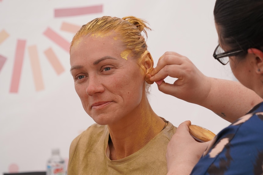 AFLW star Erin Phillips has gold body paint applied.