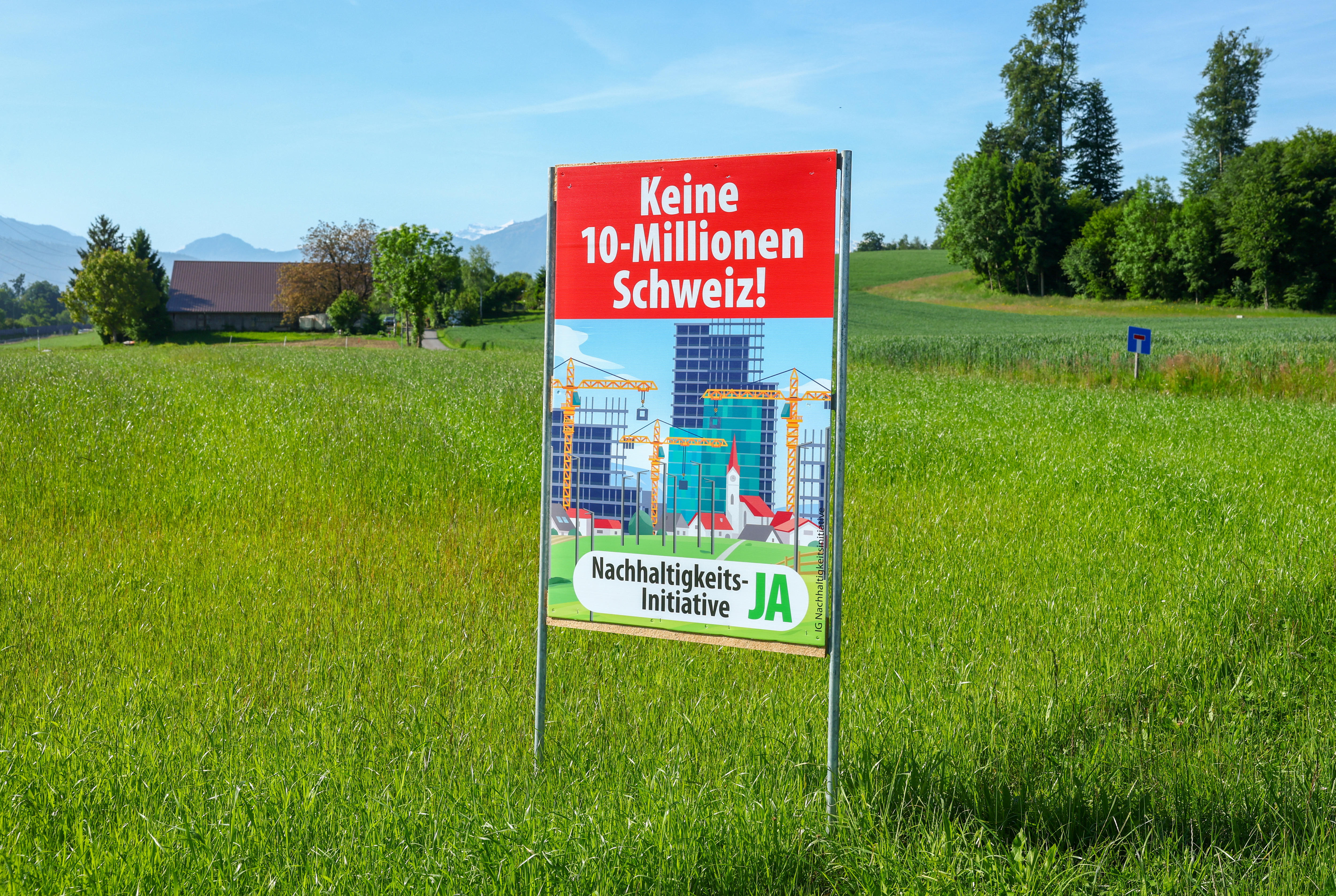 A sign stands in grass fields that reads: "No Switzerland with 10 million. Yes to the sustainability initiative."