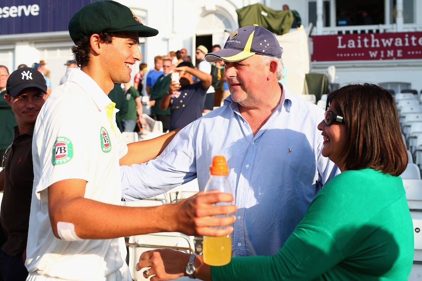 A young cricketer makes signs to hug his father and mother