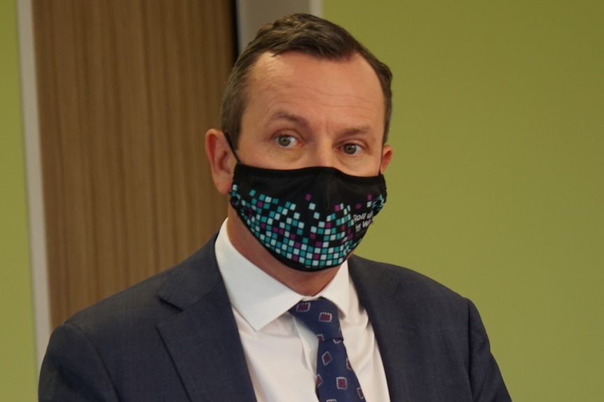 A mid shot of WA Premier Mark McGowan wearing a face mask and suit and tie indoors.