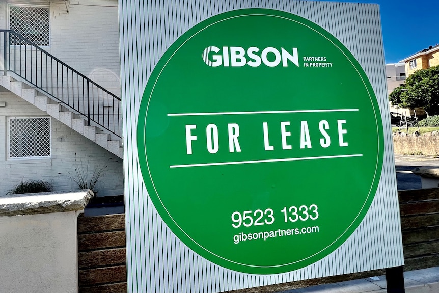 A green sign that reads "for lease" outside a block of units.