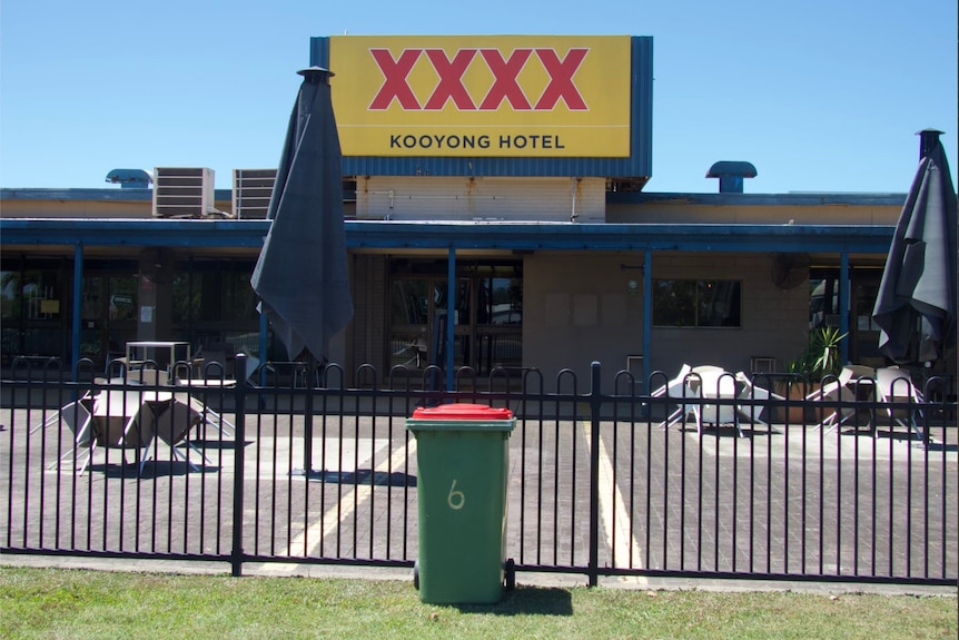 A bin outside a pub with a XXXX sign 