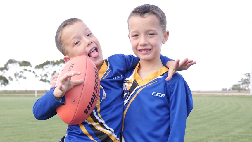 Two boys, wearing blue and yellow uniforms, from the Natimuk United Football Club in Victoria's west