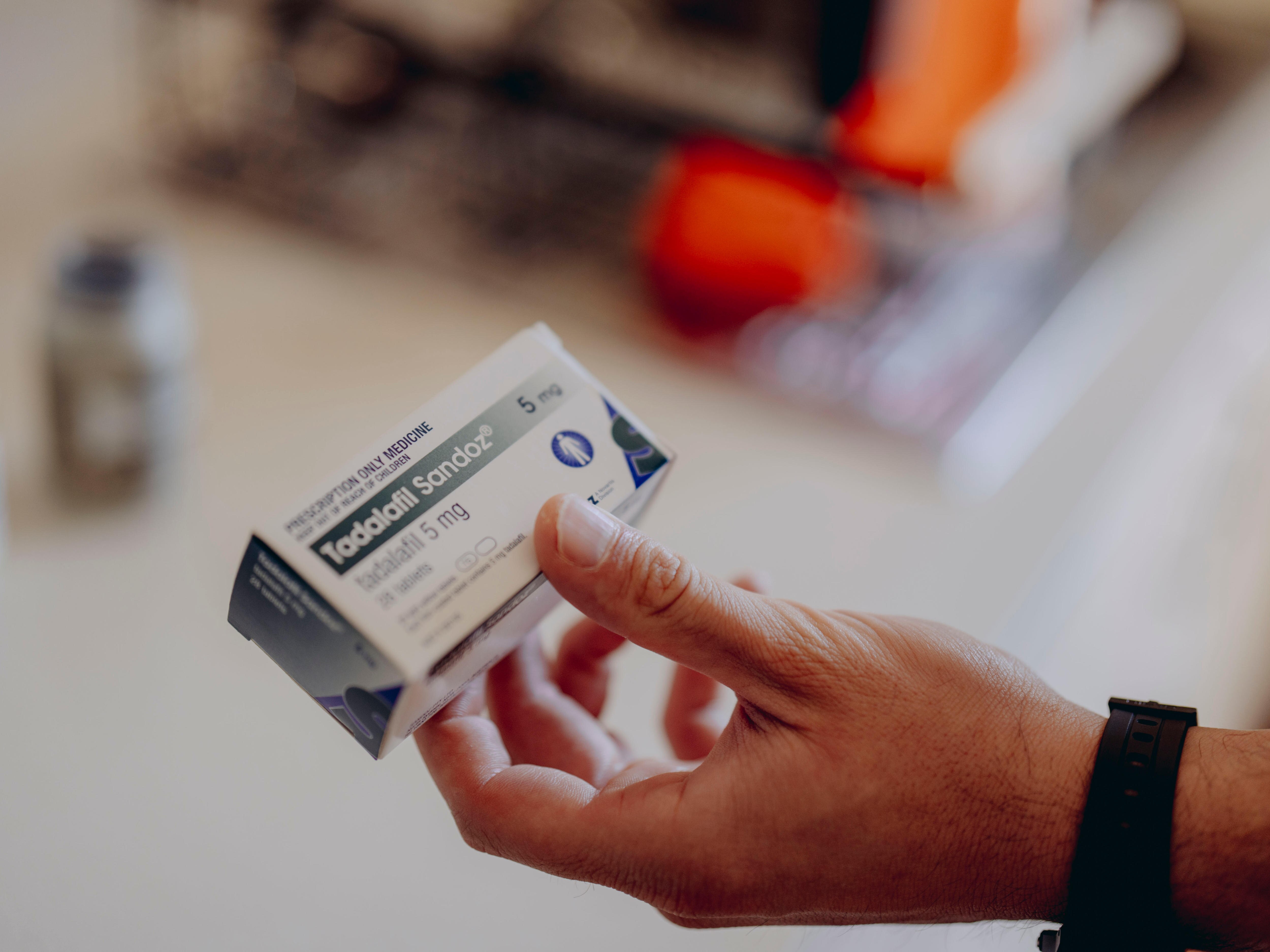 A hand shows the camera a small medication box wiht the label Tadalafil on the front.