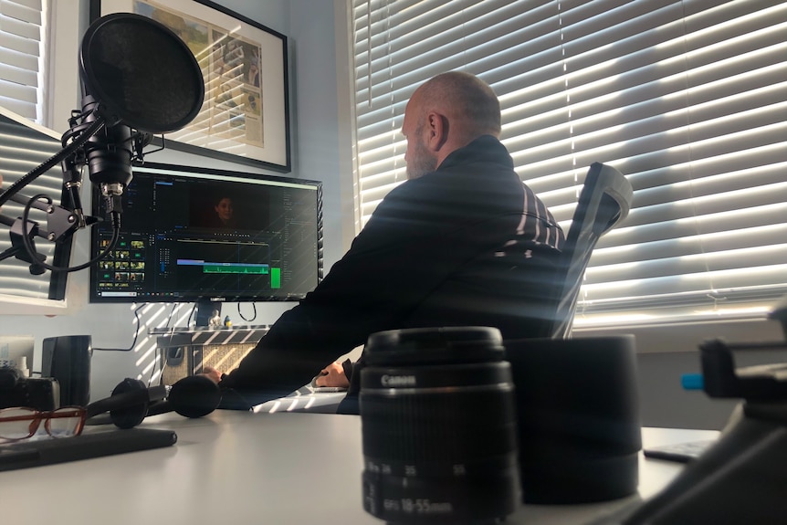 Man wearing black jumper working at a computer. 