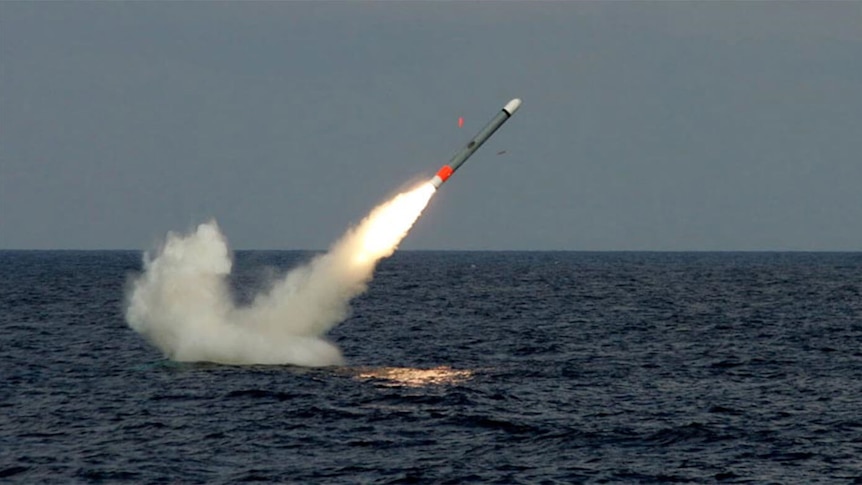 Smoke trails off a missile flying out from the ocean at an angle.