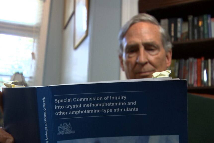 A man sitting and reading a copy ice inquiry report 