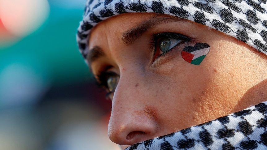 A woman with a heart-shaped Palestinian flag on her cheek 