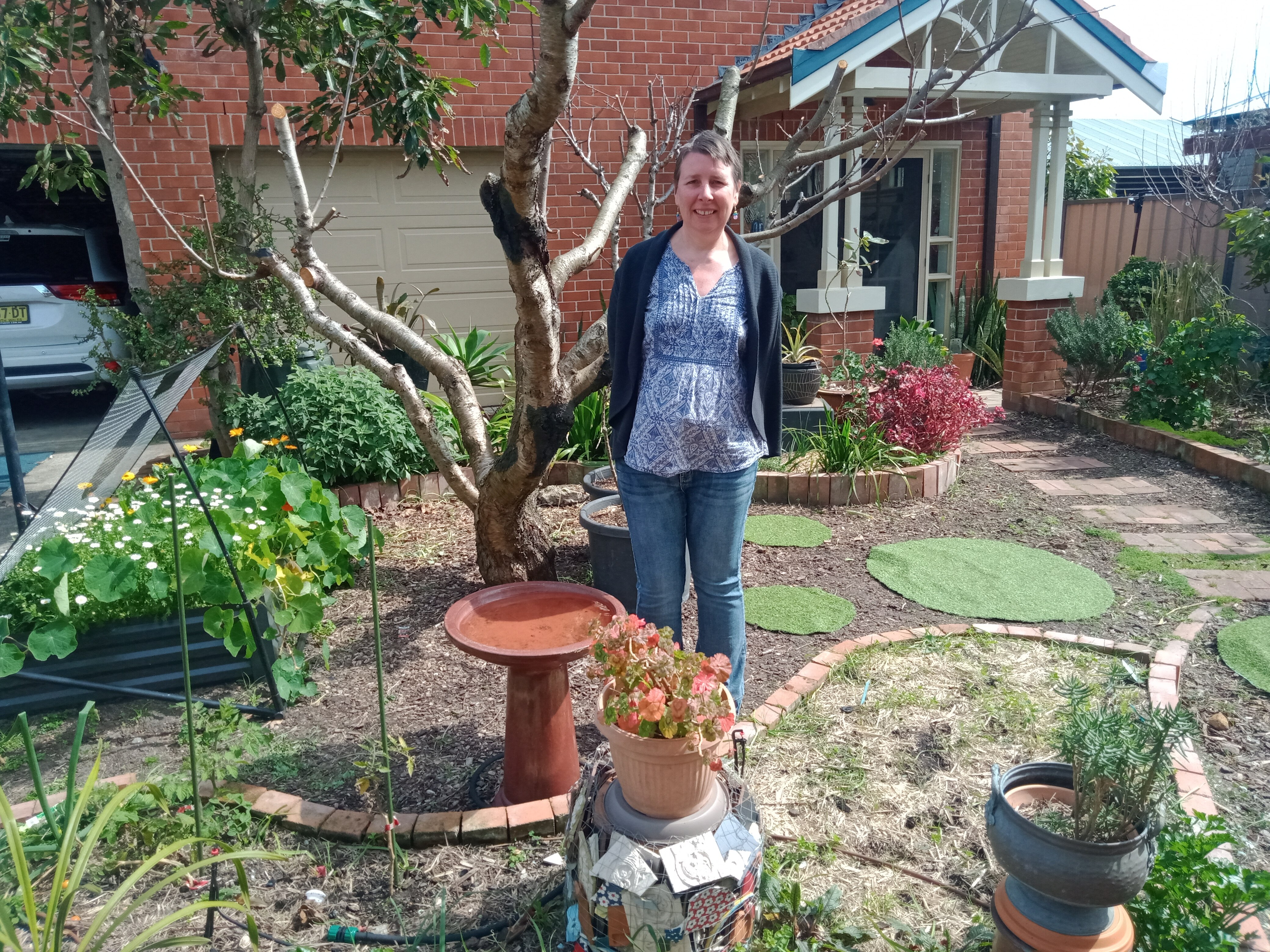 Artist Rieteka Guersen in her garden, with a mosaic she created.