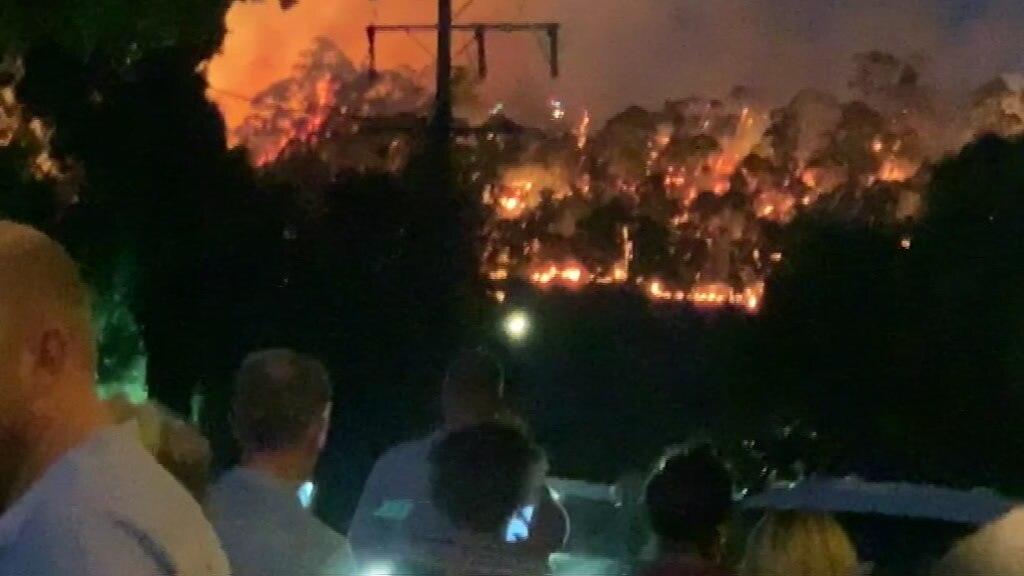 People watch on as a fire burns over the horizon near Hepburn Springs.