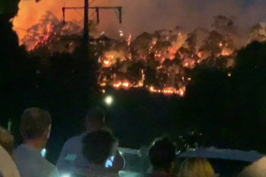 People watch on as a fire burns over the horizon near Hepburn Springs.