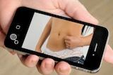 A mobile phone with an image of a woman's bare torso