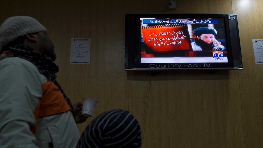 People watch a TV news report about Pakistani Taliban leader Mullah Fazlullah.